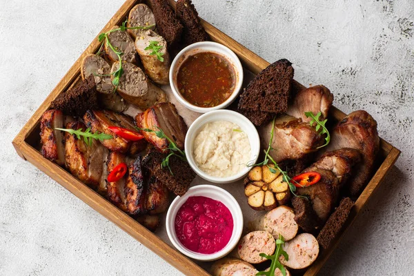 Karışık ızgara et tabağının yakın plan fotoğrafı. Sığır eti, domuz eti, kümes hayvanları, sosis, ızgara sarımsak, acı biber, mermer arka planda farklı soslar.