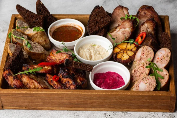Karışık ızgara et tabağının yakın plan fotoğrafı. Sığır eti, domuz eti, kümes hayvanları, sosis, ızgara sarımsak, acı biber, mermer arka planda farklı soslar.