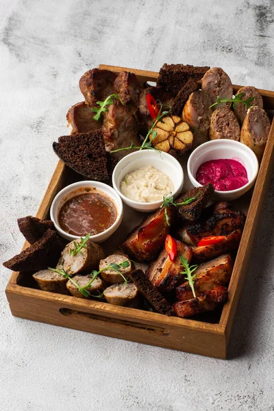 Karışık ızgara et tabağının yakın plan fotoğrafı. Sığır eti, domuz eti, kümes hayvanları, sosis, ızgara sarımsak, acı biber, mermer arka planda farklı soslar.