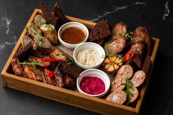 Karışık ızgara et tabağının yakın plan fotoğrafı. Sığır eti, domuz eti, kümes hayvanları, sosis, ızgara sarımsak, acı biber, mermer arka planda farklı soslar.