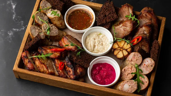 Karışık ızgara et tabağının yakın plan fotoğrafı. Sığır eti, domuz eti, kümes hayvanları, sosis, ızgara sarımsak, acı biber, mermer arka planda farklı soslar.