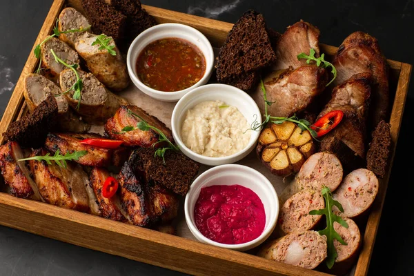 Karışık ızgara et tabağının yakın plan fotoğrafı. Sığır eti, domuz eti, kümes hayvanları, sosis, ızgara sarımsak, acı biber, mermer arka planda farklı soslar.