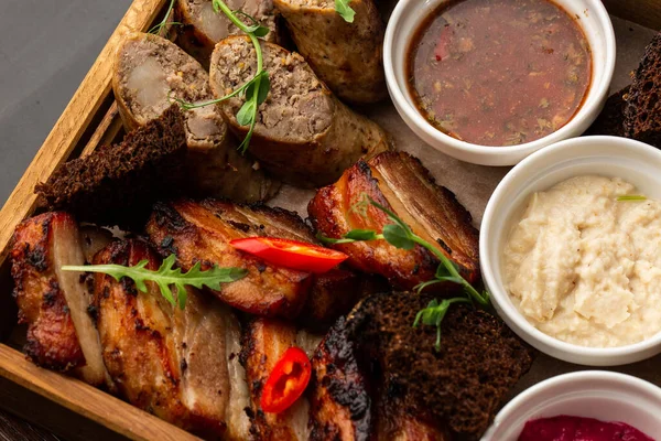 Karışık ızgara et tabağının yakın plan fotoğrafı. Sığır eti, domuz eti, kümes hayvanları, sosis, ızgara sarımsak, acı biber, mermer arka planda farklı soslar.