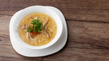 Erişteli tavuk çorbası, tavuk eti, dereotlu ve maydanozlu beyaz kâse. Ahşap arka planda izole edilmiş. Sağlıklı yemek menüsü