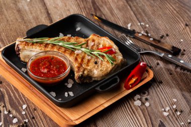 Baharatlı domuz pirzolası, biberiye ve ahşap kaplama siyah tabakta kırmızı sos. Domuz eti, sığır eti, pirzola. Üst Manzara. metin için yer