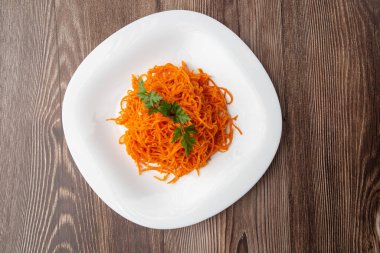Lezzetli ve baharatlı havuç spagettisi. Ahşap bir arka planda lezzetli, sulu, parlak Kore havuçları. Asya mutfağı.