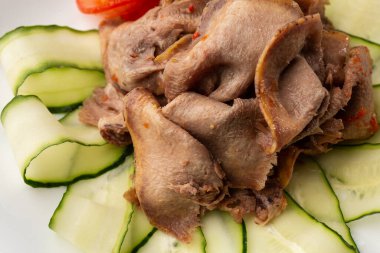 Restoran menüsünden yemek servisi. Dilimlenmiş sığır dili, ahşap zemin üzerinde salatalık, lezzetli bir aperatif..