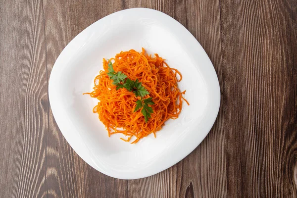 Lezzetli ve baharatlı havuç spagettisi. Ahşap bir arka planda lezzetli, sulu, parlak Kore havuçları. Asya mutfağı.