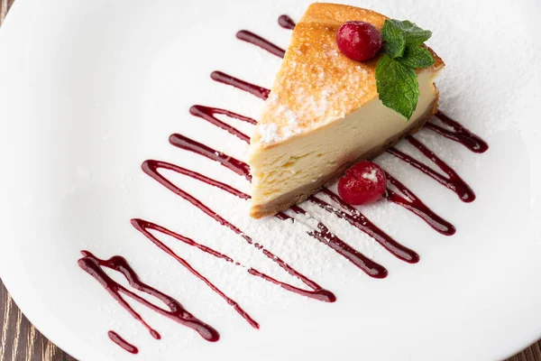 New York peynirli keki mi yoksa karamel kaplı klasik peynirli kek mi? Yakından bak. Lezzetli bir kahvaltı. Beyaz tabakta, ahşap zeminde bir parça kek.
