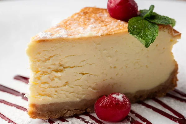 New York peynirli keki mi yoksa karamel kaplı klasik peynirli kek mi? Yakından bak. Lezzetli bir kahvaltı. Beyaz tabakta, ahşap zeminde bir parça kek.