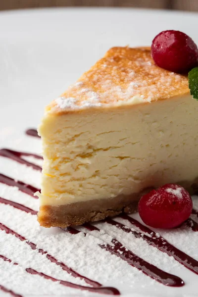 New York peynirli keki mi yoksa karamel kaplı klasik peynirli kek mi? Yakından bak. Lezzetli bir kahvaltı. Beyaz tabakta, ahşap zeminde bir parça kek.