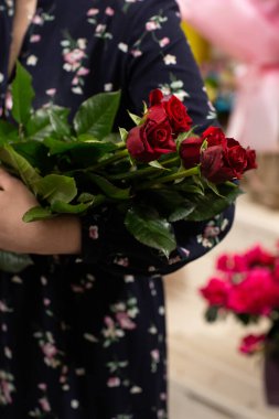 Bir buket kırmızı gül. Sevgililer günü için hediye fikri. Çiçekçi kadın elinde taze bir buket tutuyor.