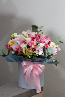 Beyaz bir masanın üzerinde yuvarlak bir kutuda güzel bir buket çiçek. Tatil hediyesi, doğum günü, düğün, anneler günü, sevgililer günü, kadınlar günü. Şapka kutusunda çiçek aranjmanı.