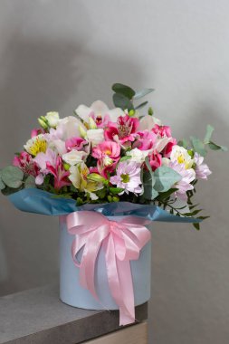 Beyaz bir masanın üzerinde yuvarlak bir kutuda güzel bir buket çiçek. Tatil hediyesi, doğum günü, düğün, anneler günü, sevgililer günü, kadınlar günü. Şapka kutusunda çiçek aranjmanı.
