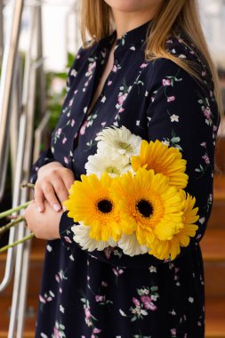 Sarı ve beyaz kasımpatılar, arka planda bulanık bir çekimde kadınların ellerinde. Güzel, parlak kasımpatılar sonbaharda çiçek açar..