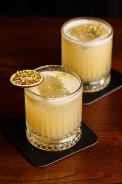 Sıcak renkli kokteyller. Mezcal kokteyl ve Alkolik Viski Penisilin Kokteyli. Bar tezgahında kokteyl bardağı..