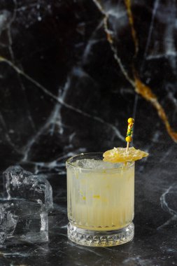 Alkolik viski, viski, limon, bal şurubu ve şekerli zencefilli kokteyl. Siyah arkaplanda kokteyl camı.