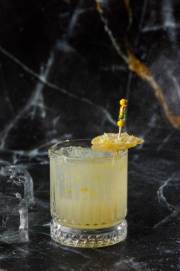 Alkolik viski, viski, limon, bal şurubu ve şekerli zencefilli kokteyl. Siyah arkaplanda kokteyl camı.