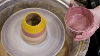 Kil çömlek üzerinde çömlek resmi. El yapımı seramik. Potter 'ın çalışanları, toprak malzemesi yapmak için fırça fırçalarını kapatıyorlar. Seramik sanat eseri boyama fırça fırçası çanak çömlek sınıfı atölye tekeri