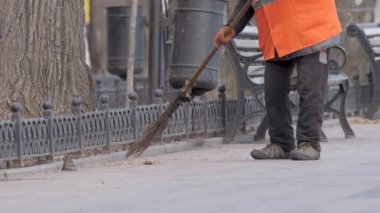 Temizlikçi kadın süpürge sopasıyla insanları sabah vakti temizliyor. Park City sokak işçisi süpürge sapı süpürüyor. Temizlikçi sokak temizleme hizmeti kamu hizmetlerini temizliyor