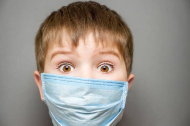 Şaşkın çocuk, maske takan çocuğu şaşırttı. Gözleri şokla açıldı. Gözleri açık, maskeli çocuk şok olmuş çocuğu şaşırttı ya da çevrimdışı öğrenime geri döndü. Covid 19 çocuk komik surat ifadesi