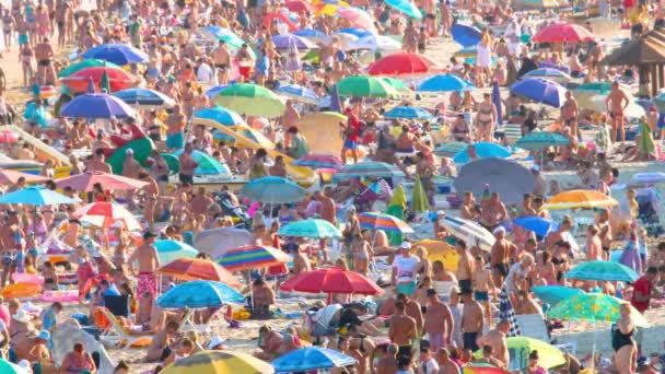 Muita gente na praia cheia de viajantes de massas. Muitas pessoas relaxantes praia praia multidão mar câmera lenta. Odessa, praia de verão do Mar Negro pessoas lotadas férias viagens marítimas na Ucrânia. Banhistas banhos de sol — Vídeo de Stock