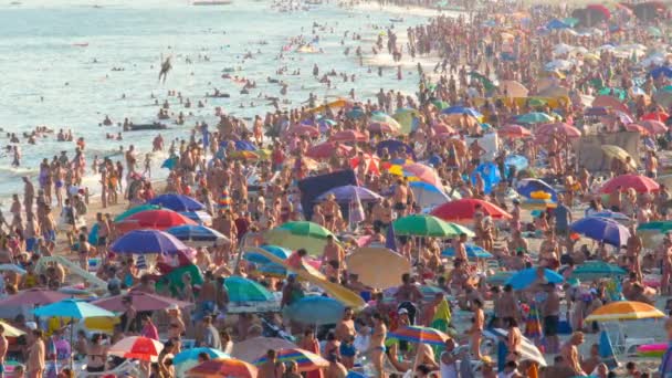 Muita gente na praia cheia de viajantes de massas. Muitas pessoas relaxantes praia praia multidão mar câmera lenta. Odessa, praia de verão do Mar Negro pessoas lotadas férias viagens marítimas na Ucrânia. Banhistas banhos de sol — Vídeo de Stock