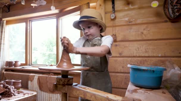 Dělám keramické hliněné dítě. Výtvarné vzdělávání tvůrčí chlapec umělec dítě hlína workshop děti řemeslo děti keramika studio keramika práce hrnčíř jíl lití. Closeup ruční keramika kolo hlína hrnčíř dítě řemeslo — Stock video