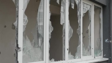 Ukrayna 'daki bir sivilin patlama camına ateş etmesi sonucu. Parçalanmış cam hasarı Ukrayna savaş tahribatı bina hasarı. Cam kırıkları pencere aralığını tahrip etti.