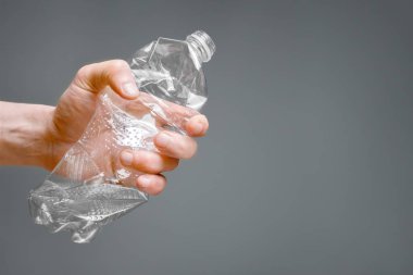Raised hands holding crumpled plastic bottle hand squeeze bottle water plastic recycle reuse reduce waste concept. Crumpled bottle pet plastic resize or zero waste plastic hand recycling garbage crush