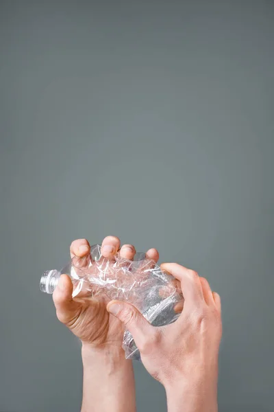 Raised hands holding crumpled plastic bottle hand squeeze bottle water plastic recycle reuse reduce waste concept. Crumpled bottle pet plastic resize or zero waste plastic hand recycling garbage crush