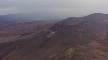 Bulutların arka planına karşı dağın havadan görünüşü ve bir dağ sırası