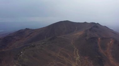 Bulutların arka planına karşı dağın havadan görünüşü ve bir dağ sırası