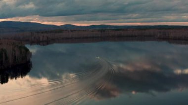 Gölde yüzen bir motorlu teknenin havadan görüntüsü.