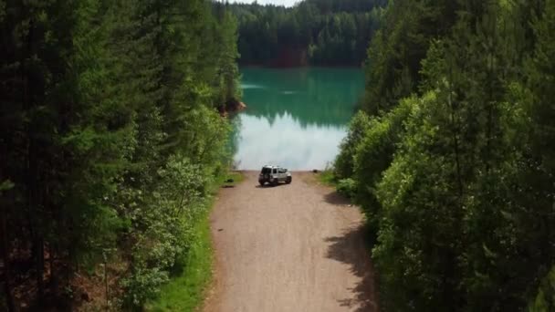 木々の間の湖の近くの道路上の旅行者の車の空中ビュー — ストック動画