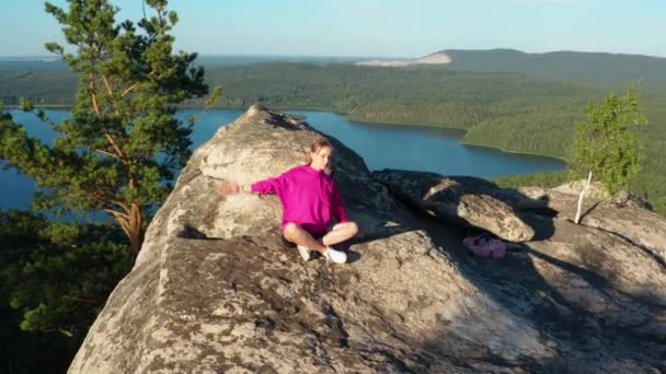 Luftaufnahme eines Mädchens, das Fitness und Yoga auf einem Felsen macht — Stockvideo