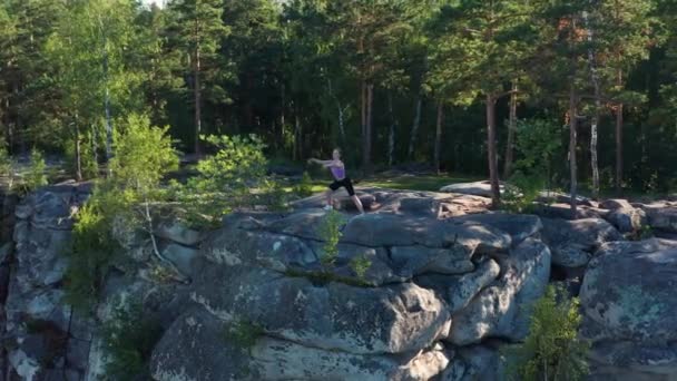 Luftaufnahme eines Mädchens, das Fitness und Yoga am Rande einer Klippe macht — Stockvideo