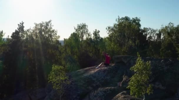 Вид с воздуха девушки, занимающейся фитнесом и йогой на скале — стоковое видео