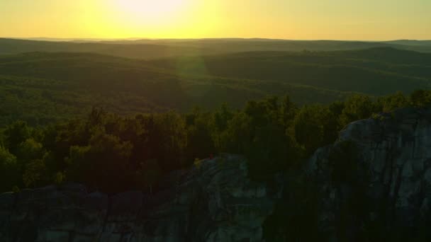 Vista aérea de una chica meditando sobre una roca al atardecer — Vídeo de stock