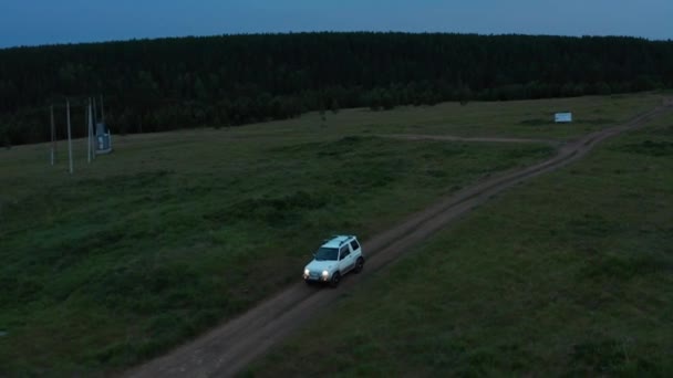 Aerial view of a car driving in nature on a field at sunset — Video Stock