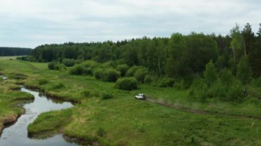Nehir kenarındaki doğada giden bir arabanın havadan görüntüsü.