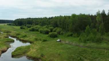 Nehir kenarındaki doğada giden bir arabanın havadan görüntüsü.