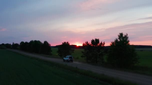 Aerial view of a car driving in nature on a field at sunset — Stockvideo