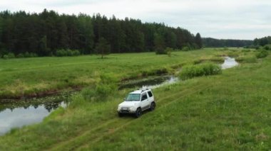 Nehir kenarındaki doğada giden bir arabanın havadan görüntüsü.