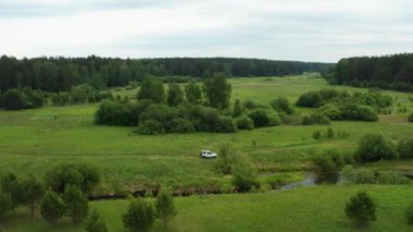 Nehir kenarındaki doğada giden bir arabanın havadan görüntüsü.
