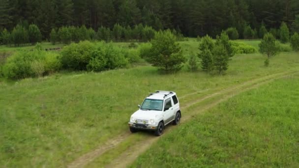 Blick von oben auf einen Jeep, der auf einem Feldweg in der Natur fährt — Stockvideo