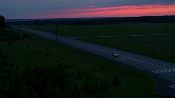 Aerial view of a car on the road on the background of sunset — Stock Video