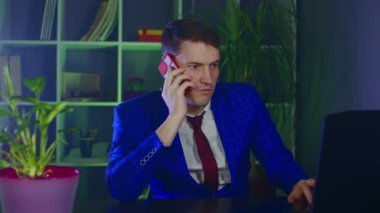 Ciddi iş adamları cep telefonuyla konuşur, laptopta ofiste çalışır. Modern iş yerindeki akıllı telefon konuşmaları sırasında duygusal erkek girişimci çığlıkları atıyor..