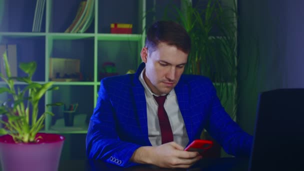 Thoughtful businessman using mobile phone in modern workplace. Young man browsing smartphone, sitting in in office. — Stock Video