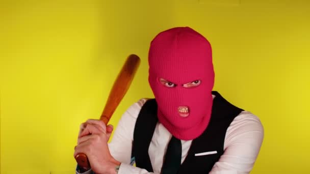 Hombre de pasamontañas rosa con bate de béisbol. Hooligan con máscara y murciélago en las manos. Un hombre en un negocio estricto traje elegante con un bate de madera en sus manos — Vídeo de stock